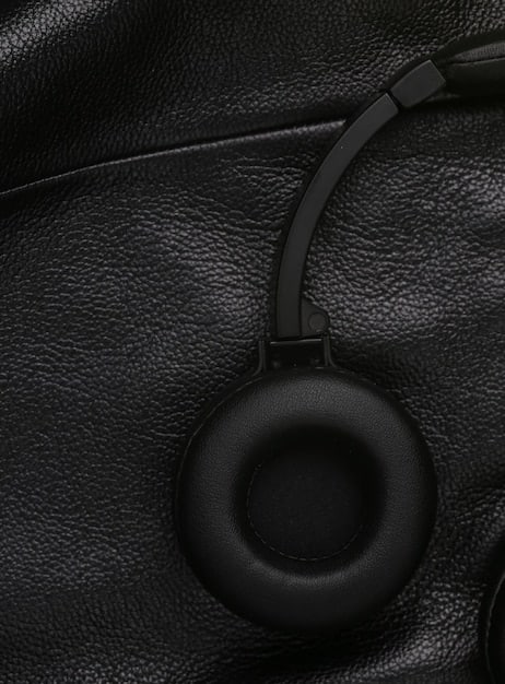 A close-up shot of the earcups of the SoundWave Pro headphones, highlighting the texture of the leather and the stitching, with a blurred background of a music studio.