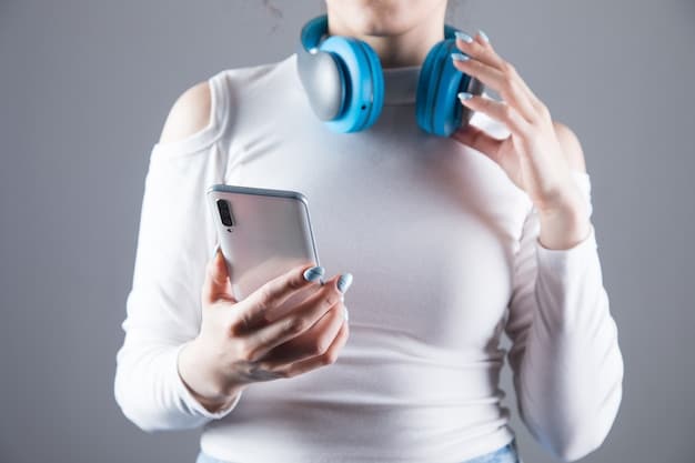 A close-up shot of the Aura headset's earcup, showing touch controls and small details, with a smartphone displaying the companion app interface in the background.